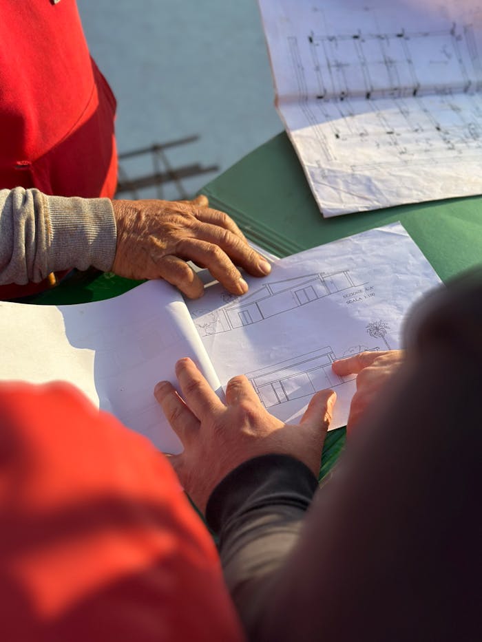 A team of architects examining architectural blueprints at an outdoor construction site.